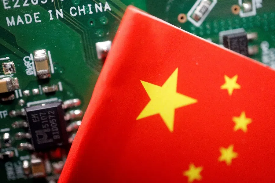 A Chinese flag is displayed next to a “Made in China” sign seen on a printed circuit board with semiconductor chips, in this illustration picture taken on 17 February 2023. (Florence Lo/Illustration/Reuters)