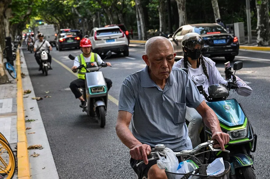 People travel on the road in the Huangpu district of Shanghai, China, 30 September 2024. (Hector Retamal/AFP)