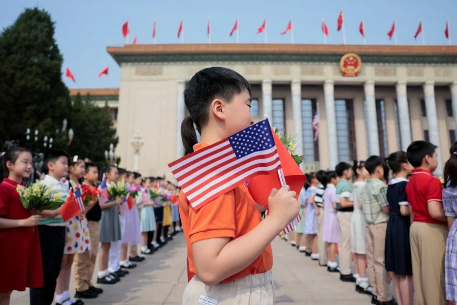 A boy holding a US flag and China flag stands alongside other children ahead of US President Donald Trump's arrival at the Great Hall of the People in Beijing, China, on 14 May 2026.