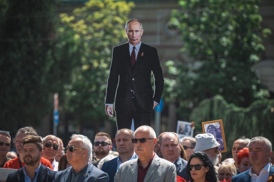 A man holds a cutout of Russian President Vladimir Putin during the "Immortal Regiment" march in Belgrade on 9 May 2022. (Andrej Isakovic/AFP)