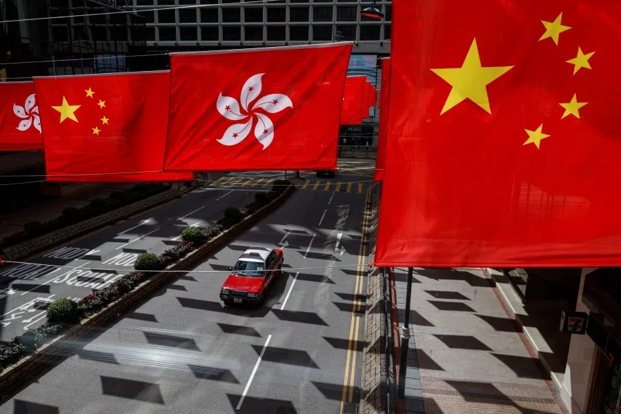 A taxi drives under Chinese and Hong Kong flags outside a shopping mall in Hong Kong, China, on 5 July 2023. (Tyrone Siu/Reuters)