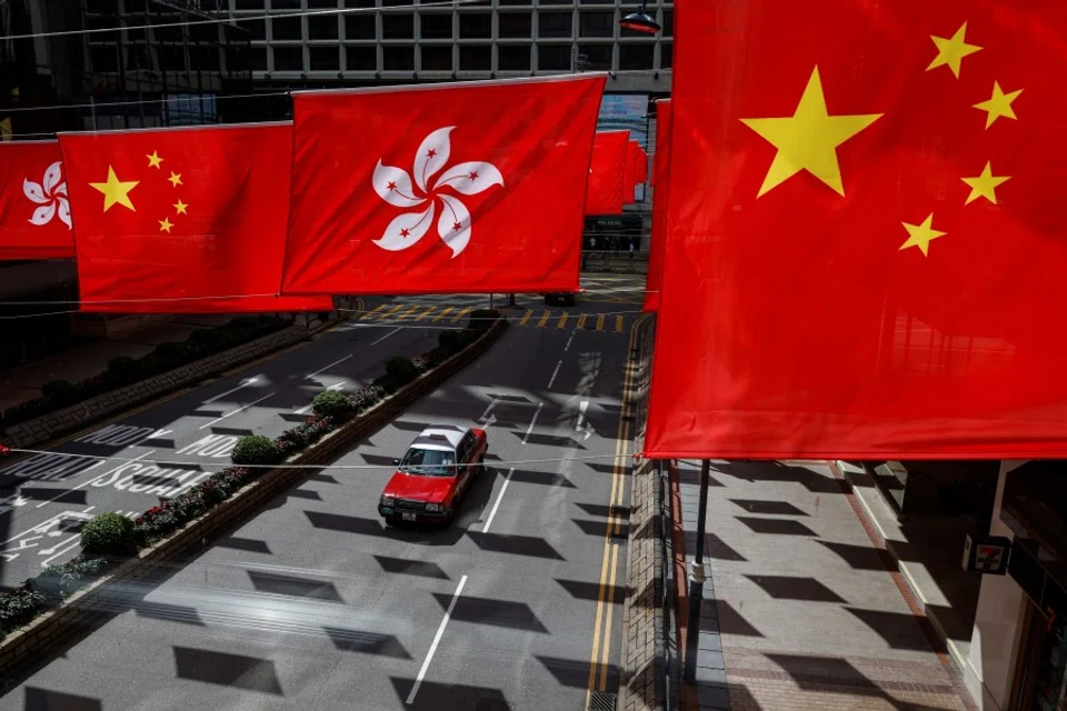 A taxi drives under Chinese and Hong Kong flags outside a shopping mall in Hong Kong, China, on 5 July 2023. (Tyrone Siu/Reuters)