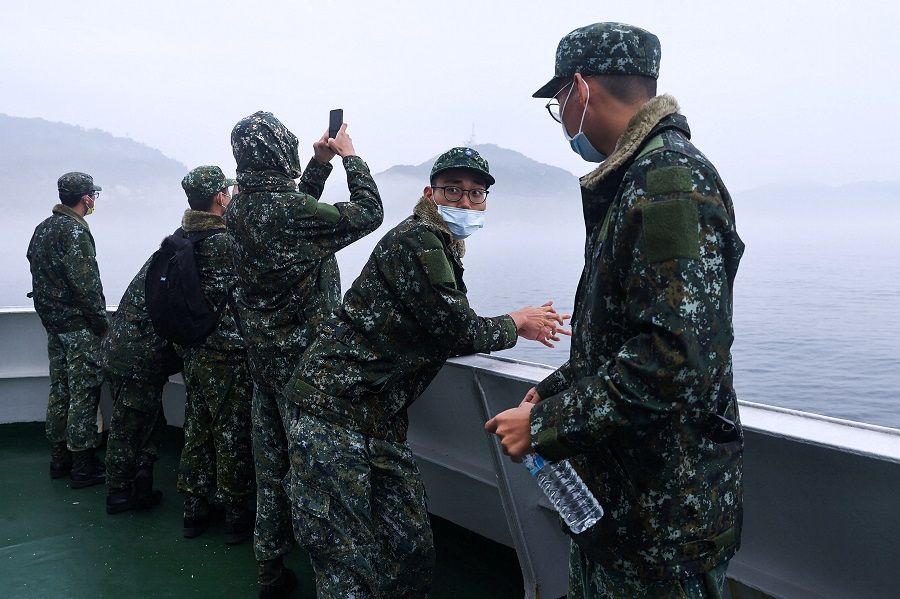 A group of soldiers who finished a month of training stand on the deck of the ferry, and are about to finish the rest of their three-month mandatory military service in Dongyin, Matsu, Taiwan, 17 March 2022. (Ann Wang/Reuters)
