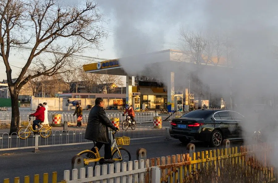 People ride bicycles past a gas station next to clouds of steam rising from a steam exhaust pipe on a cold winter day in Beijing, China, on 22 January 2026. (Maxim Shemetov/Reuters)