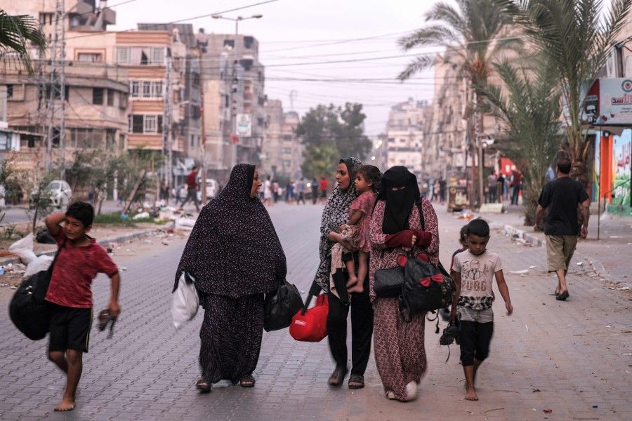 Fleeing women walk with the children along a street in Gaza City on 11 October 2023. (Mohammed Abed/AFP)