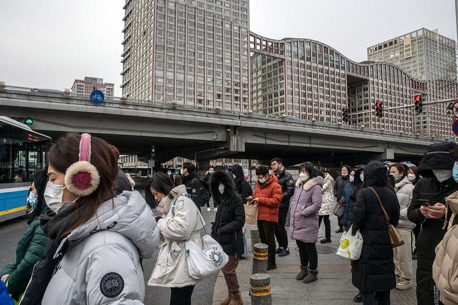 Pedestrians wait to cross a road in Beijing, China, on 3 February 2023. (Bloomberg)