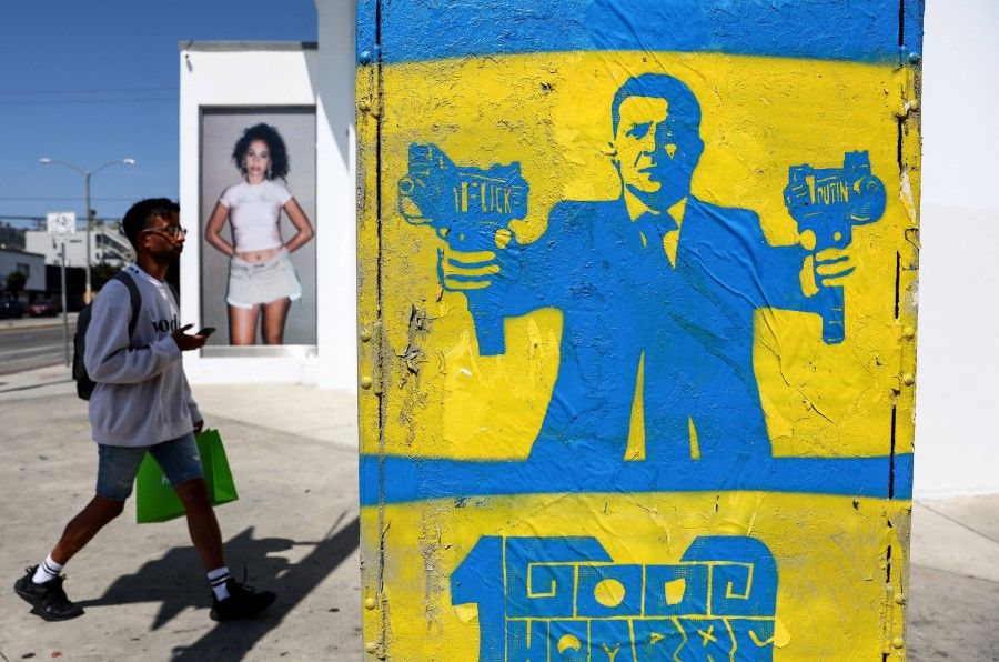 Street art depicts Ukrainian President Volodymyr Zelenskyy gripping submachine guns as a person walks past on Melrose Avenue on 30 March 2022 in Los Angeles, California. (Mario Tama/Getty Images/AFP)