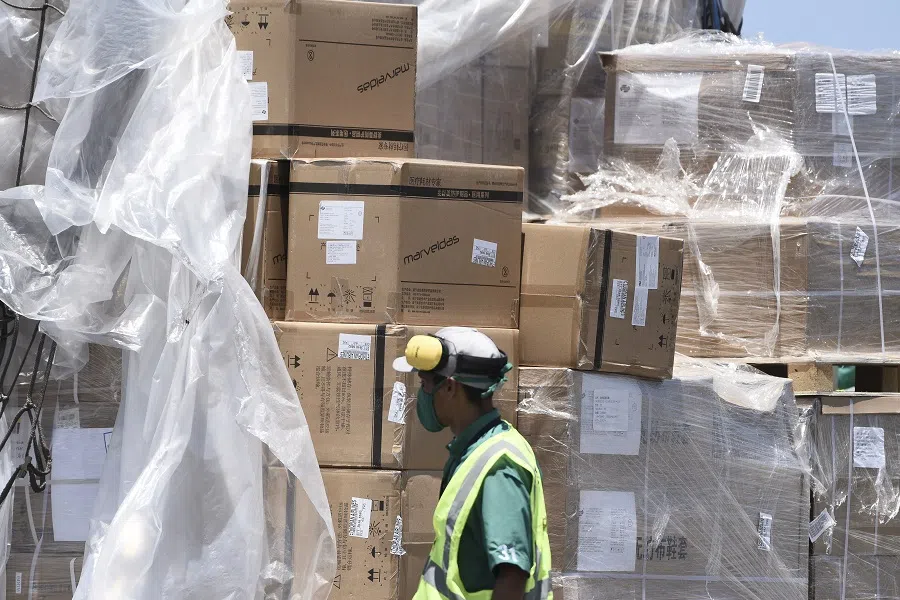 A worker wearing a protective mask unloads pallets of humanitarian aid delivered from China at Simon Bolivar International Airport in Maiquetia, Vargas state, Venezuela, on 28 March 2020. (Carlos Becerra/Bloomberg)
