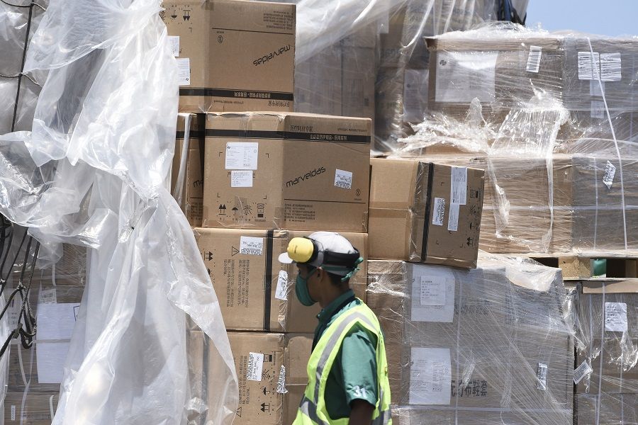 A worker wearing a protective mask unloads pallets of humanitarian aid delivered from China at Simon Bolivar International Airport in Maiquetia, Vargas state, Venezuela, on 28 March 2020. (Carlos Becerra/Bloomberg)