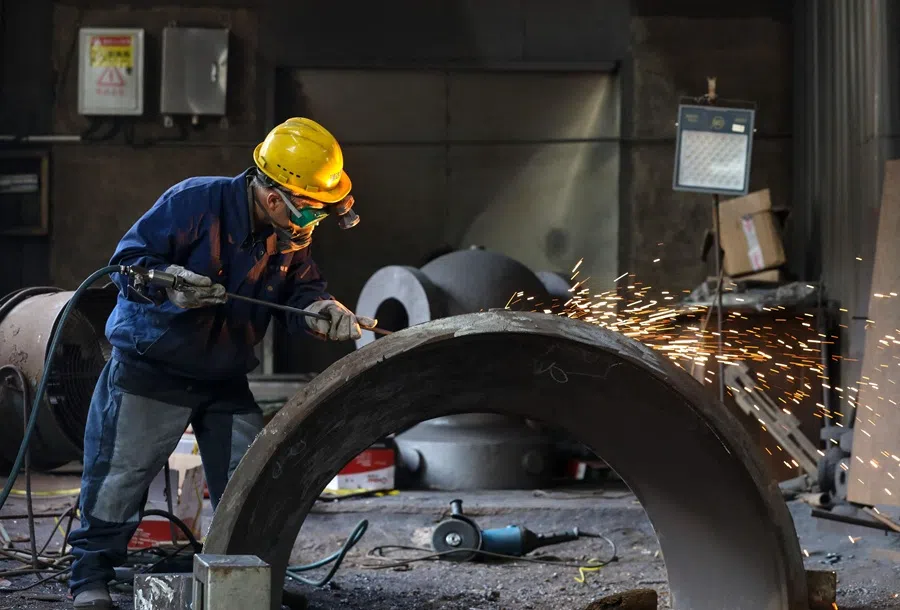 A worker polishes steel parts at a machinery manufacturing company in Hangzhou, Zhejiang province, China, on 16 June 2025. (AFP)