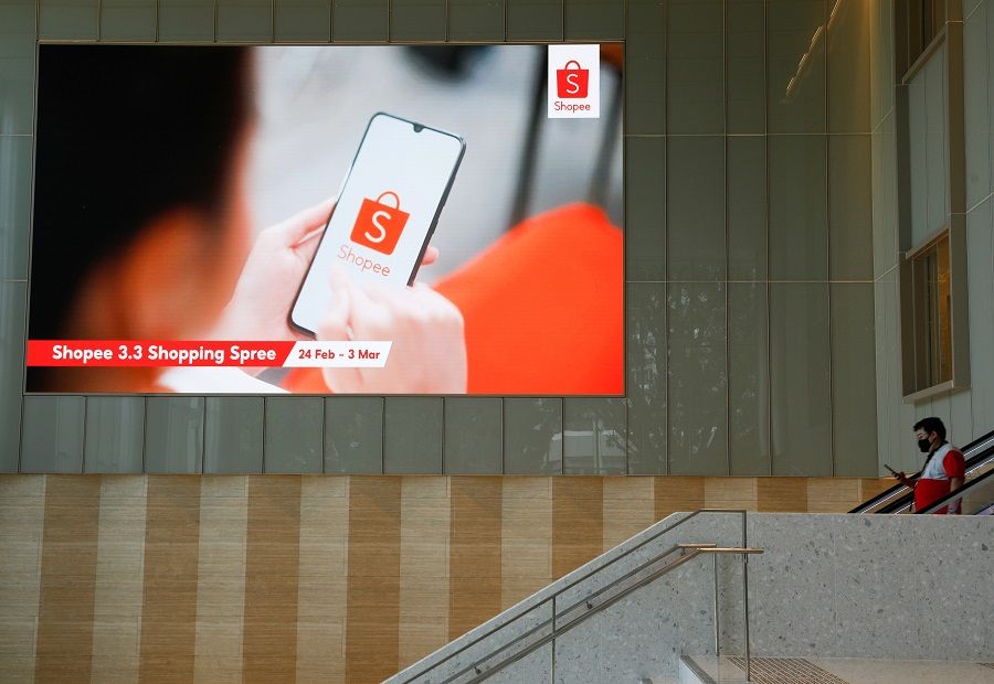 A man passes in front of a video wall showing advertisements of Shopee, the e-commerce arm of Southeast Asia's Sea Ltd, at their office in Singapore, 5 March 2021. (Edgar Su/File Photo/Reuters)