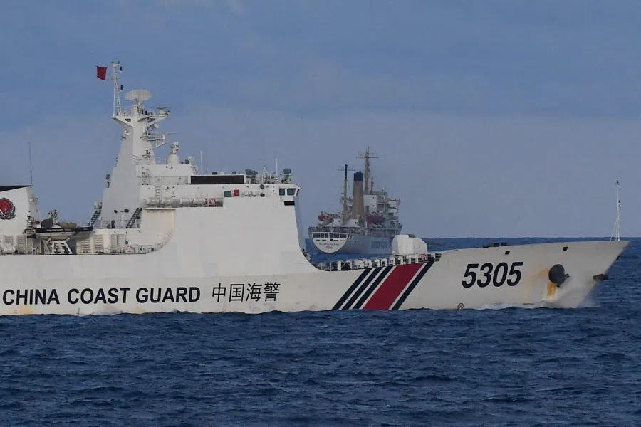 A Chinese Coast Guard ship sails near a Philippine vessel (centre) that was part of a convoy of civilian boats in the disputed South China Sea on 10 December 2023. (Ted Aljibe/AFP)