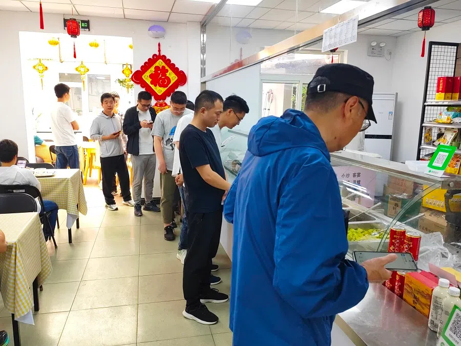 People queue up to order food at a community canteen in Beijing.