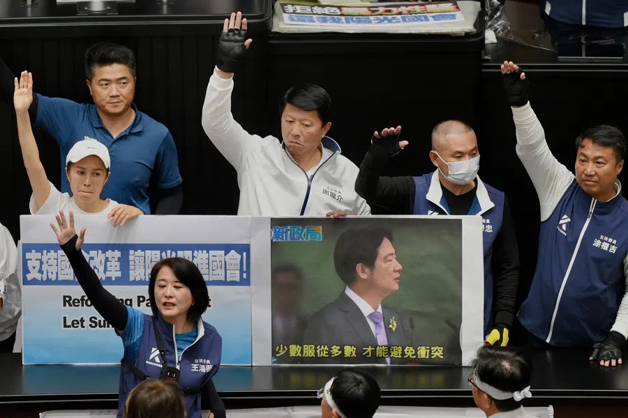Main opposition Kuomintang legislators raise their hands next to a placard showing Taiwan’s President Lai Ching-te while voting for the parliament reform bill at the Parliament in Taipei, on 21 May 2024. (Sam Yeh/AFP)