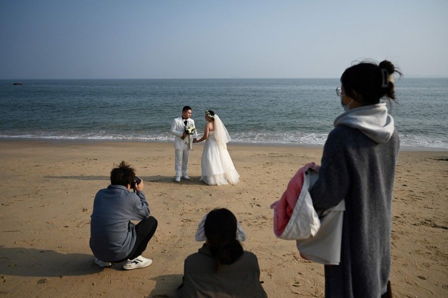 A wedding couple poses for photos on the beach at Xiamen, in China's southeast Fujian province, opposite Taiwan's Kinmen Island on 11 January 2024. (Greg Baker/AFP)