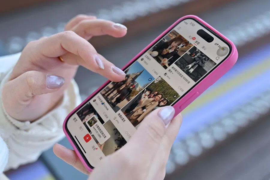 A photo illustration shows a woman holding her smartphone displaying the Chinese social networking and e-commerce app Xiaohongshu, also known as RedNote, in Beijing on 15 January 2025. (Adek Berry/AFP)