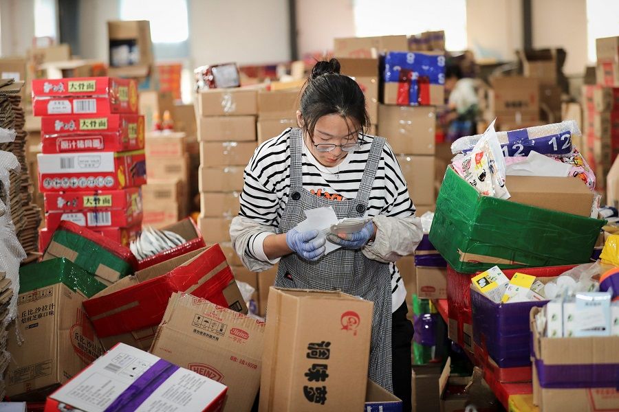An employee checks the delivery information for packages ahead of the upcoming Singles' Day Festival at an e-commerce warehouse in Lianyungang, Jiangsu, China, 2 November 2020. (STR/AFP)