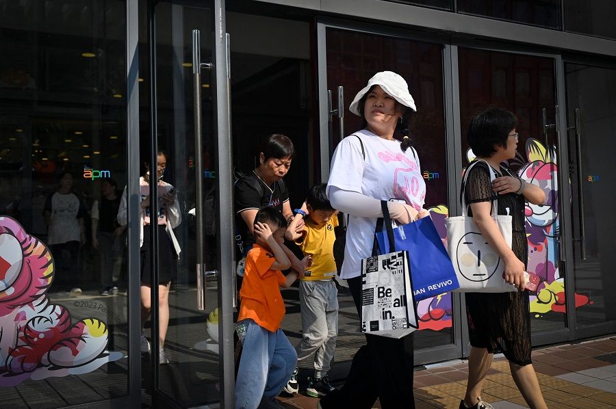 A group of people walk out of a mall in a business district in Beijing, China, on 14 August 2023. (Wang Zhao/AFP)