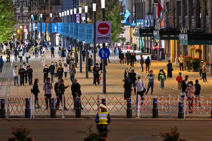 People walk along a pedestrian street surrounded by shops and shopping malls in Shanghai on 24 October 2022. (Hector Retamal/AFP)