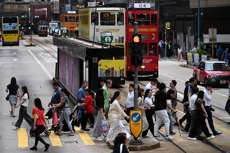 People cross a street in Hong Kong on 15 July 2025. (Peter Parks/AFP)