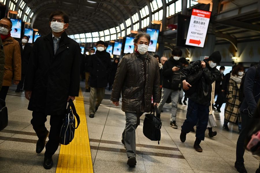 Mask-clad commuters make their way to work during the morning rush hour at the Shinagawa train station in Tokyo on 28 February 2020. (Charly Triballeau/AFP)