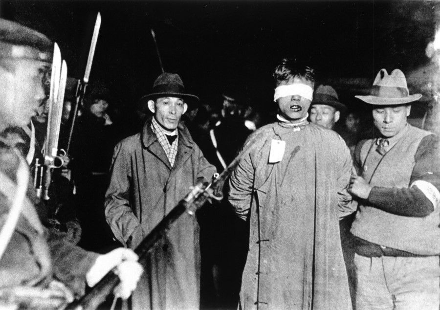 Plainclothes Japanese troops arresting a Chinese resistance fighter in the "28 January" incident of 1932. The blindfolded man has been beaten and has blood in his mouth. While his whole face is not seen, his proud refusal to back down in the face of the enemies' knives and guns is strongly felt.