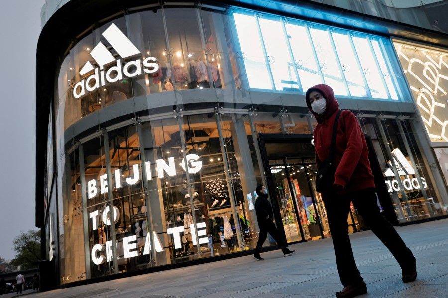 People walk past an Adidas store in a shopping district following an outbreak of the coronavirus disease (Covid-19) in Beijing, China, 5 April 2021. (Thomas Peter/Reuters)