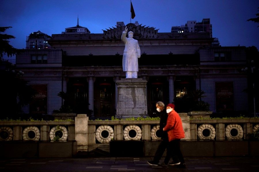 A couple wearing face masks are seen in front of a statue of former Chinese leader Mao Zedong on a street in Wuhan, 29 March 2020. (Aly Song/REUTERS)