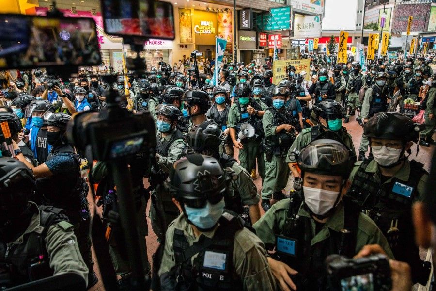 Riot police clear a street as protesters gathered to rally against a new national security law in Hong Kong on 1 July 2020, on the 23rd anniversary of the city's handover from Britain to China. A man found in possession of a Hong Kong independence flag became the first person to be arrested under Beijing's new national security law for the city, police said on 1 July. (Dale de la Rey/AFP)