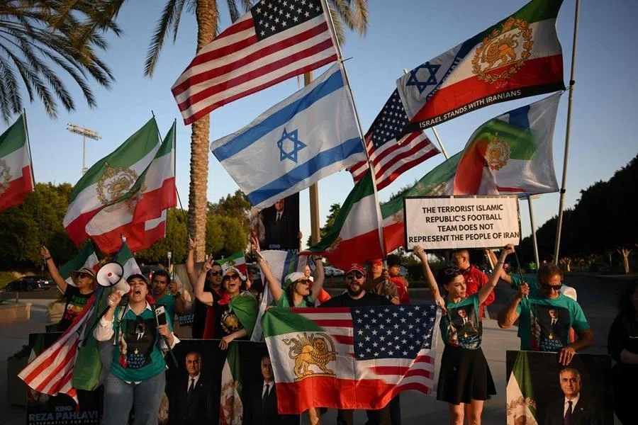 People hold pre-revolutionary Iranian flags as they protest the Iranian regime outside Carson Sports Park before Iran’s training session in Los Angeles on 14 June 2026.
