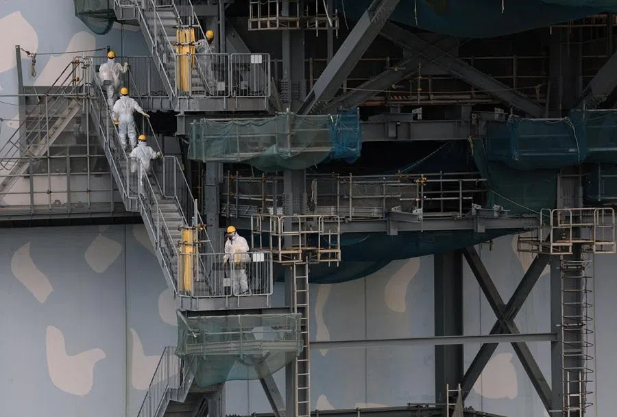 Workers wearing protective suits and masks conduct a decommissioning operation at No. 2 reactor building at the tsunami-crippled Fukushima Daiichi nuclear power plant in Okuma town, Fukushima prefecture, Japan, 22 January 2026, ahead of the 15-year anniversary of the 11 March 2011 earthquake and tsunami disaster that killed thousands and triggered the worst nuclear accident since Chernobyl. (Issei Kato/Reuters)