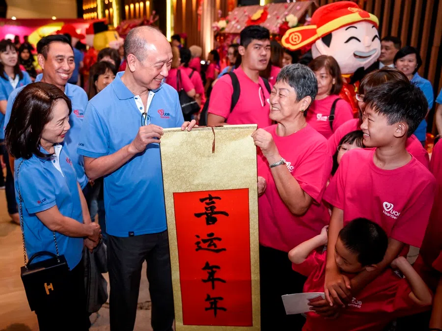 Wee Ee Cheong (second from left) and Mrs Wee present a Chinese calligraphy scroll for Chinese New Year to a family at a reunion dinner event on 13 January 2020. (Photo provided by UOB)