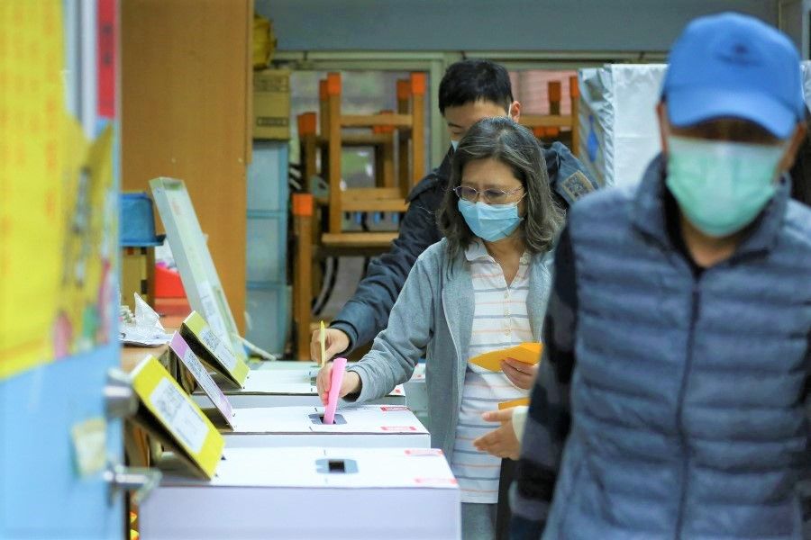 People wearing face masks to prevent the spread of Covid-19, cast their vote at a polling station while participating in a four-question referendum in Taipei, Taiwan, 18 December 2021. (Annabelle Chih/Reuters)