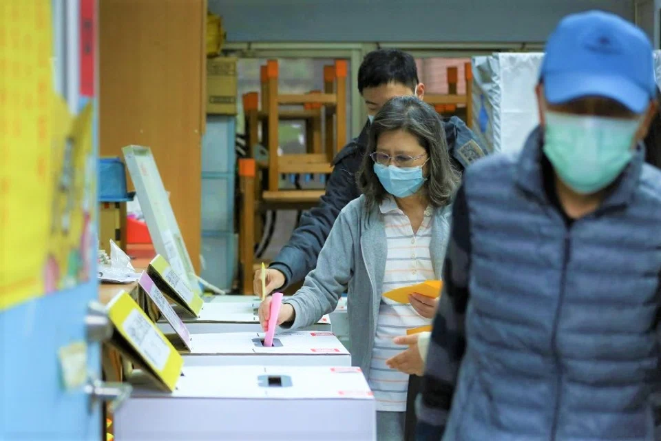 People wearing face masks to prevent the spread of Covid-19, cast their vote at a polling station while participating in a four-question referendum in Taipei, Taiwan, 18 December 2021. (Annabelle Chih/Reuters)