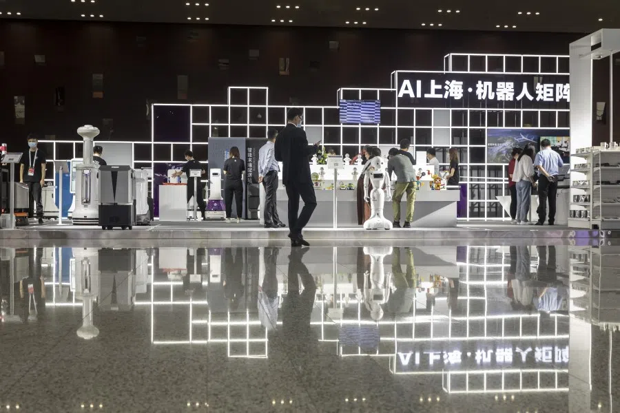 Attendees browse as a humanoid robot stands in the exhibition display area at the World AI Conference in Shanghai, 9 July 2020. (Qilai Shen/Bloomberg)