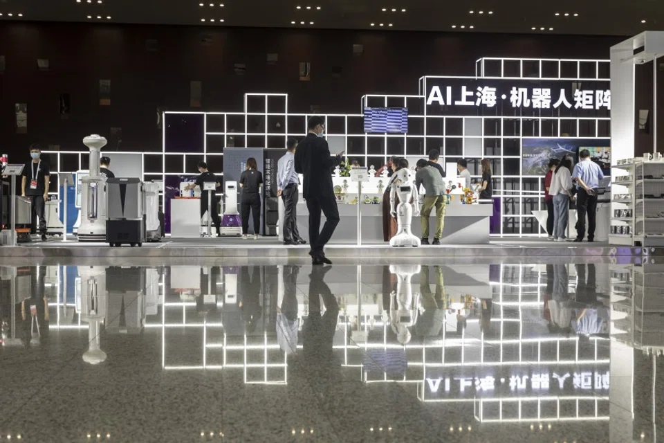 Attendees browse as a humanoid robot stands in the exhibition display area at the World AI Conference in Shanghai, 9 July 2020. (Qilai Shen/Bloomberg)