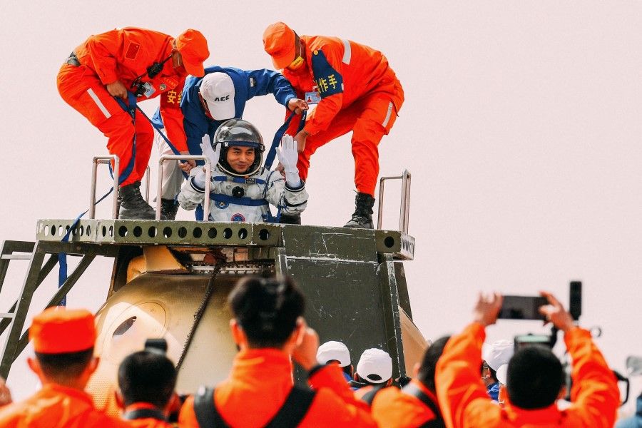 Chinese astronaut Ye Guangfu (centre) is assisted by officials to leave the capsule of the Shenzhou-13 spacecraft after landing in China's Inner Mongolia on 16 April 2022. (AFP)