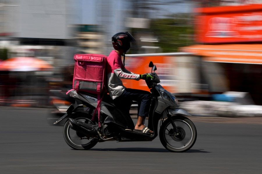 A food delivery motorist rides on a street as deliveries rise due to lockdown restrictions introduced to try to halt a surge in cases of the Covid-19 coronavirus in Phnom Penh on 26 April 2021. (Tang Chhin Sothy/AFP)