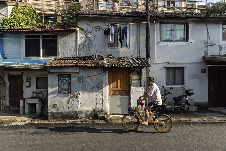 A commuter rides his bicycle through an older neighborhood in Shanghai, China, on 30 August 2021. (Qilai Shen/Bloomberg)
