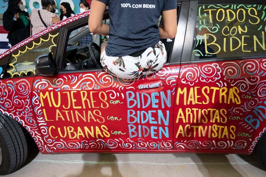 A woman sits in a car painted with Spanish slogans in support of Joe Biden as he speaks during a drive-in rally in Miramar, Florida on 13 October 2020. (Jim Watson/AFP)