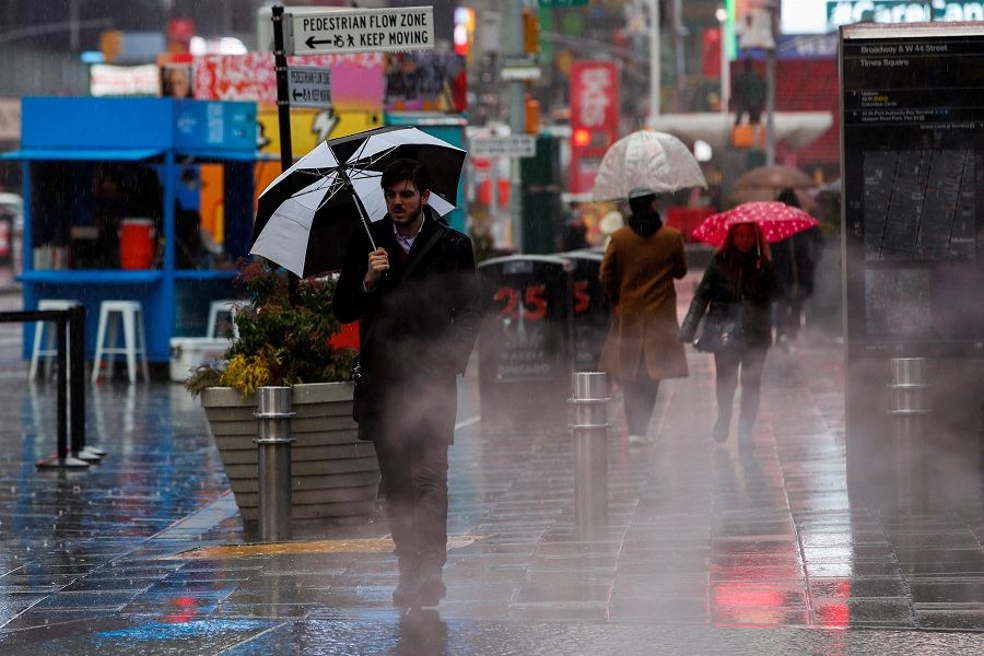 People walk around Times Square during the pass of a winter storm in New York, US, 25 February 2022. (Eduardo Munoz/Reuters)