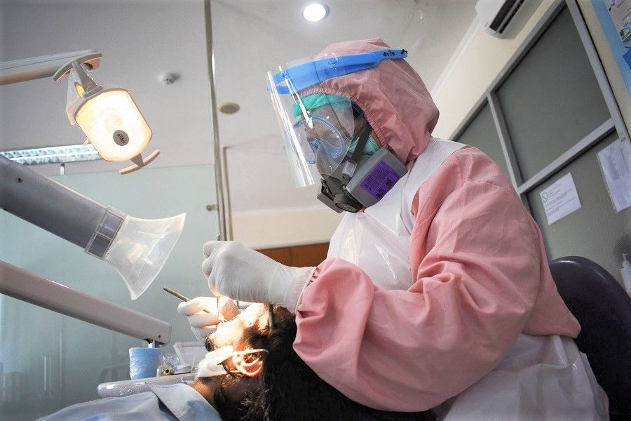 A dentist tends to her patient at a dental clinic in Bandung, Indonesia, on 19 January 2022. (Timur Matahari/AFP)