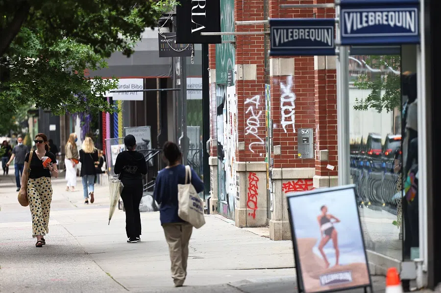 People walk past graffiti on a storefront in the Soho neighborhood in Manhattan on 4 June 2021 in New York City, US. (Michael M. Santiago/Getty Images/AFP)