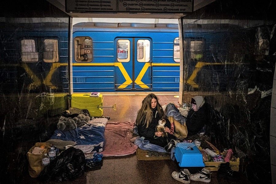 A woman hugs her cat inside a subway wagon in a underground metro station used as a bomb shelter in Kyiv, Ukraine, on 8 March 2022. (Dimitar Dilkoff/STF/AFP)