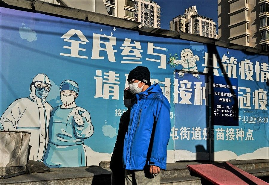 People wearing face masks amid the Covid-19 pandemic walk along a street in Beijing, China, on 11 December 2022. (Noel Celis/AFP)