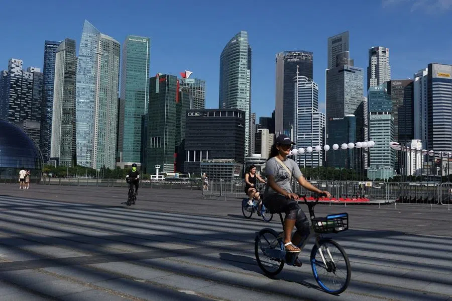 People ride bikes past the skyline of the central business district in Singapore on 13 June 2025. (Edgar Su/Reuters)