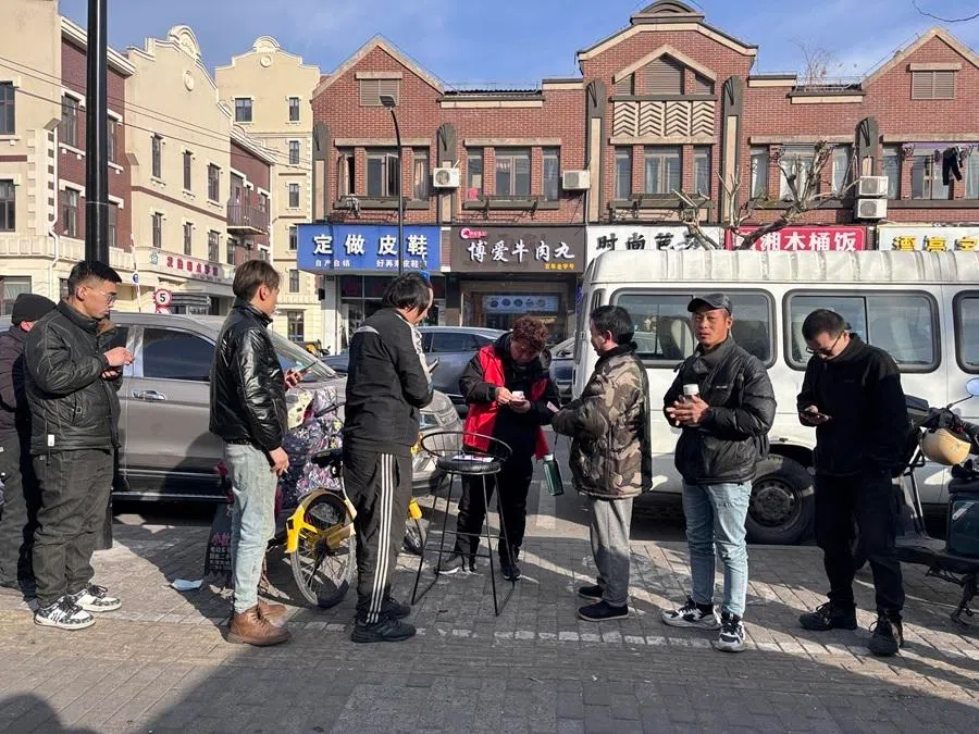 A supervisor gives out salaries to gig workers outside a labour agency in Shanghai, January 2025.