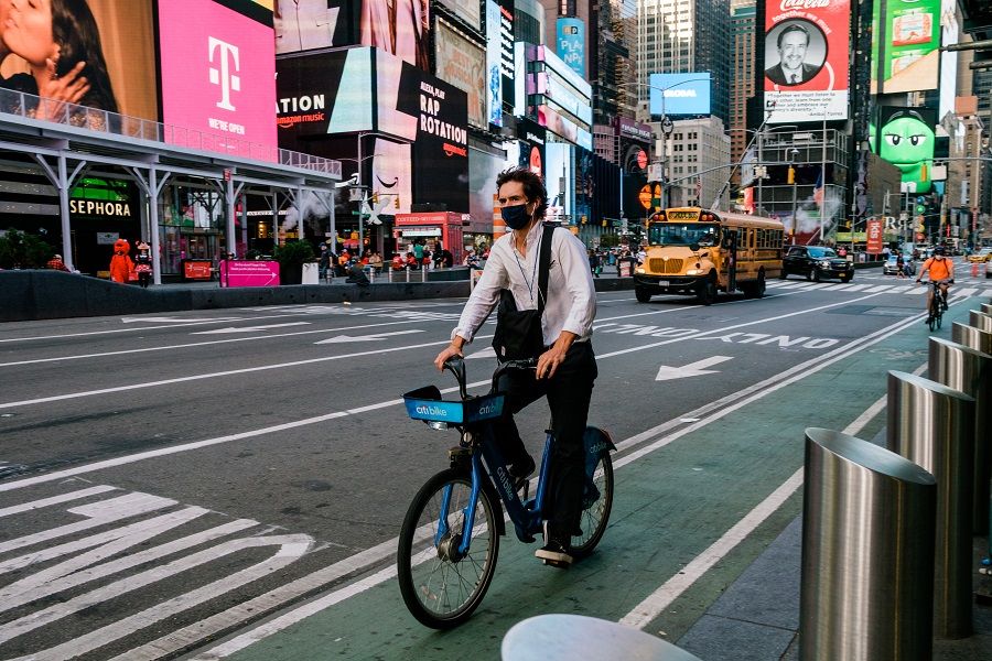 A person wears a protective mask while riding a bicycle through the Times Square neighbourhood of New York, US, on 10 November 2020. (Gabriela Bhaskar/Bloomberg)