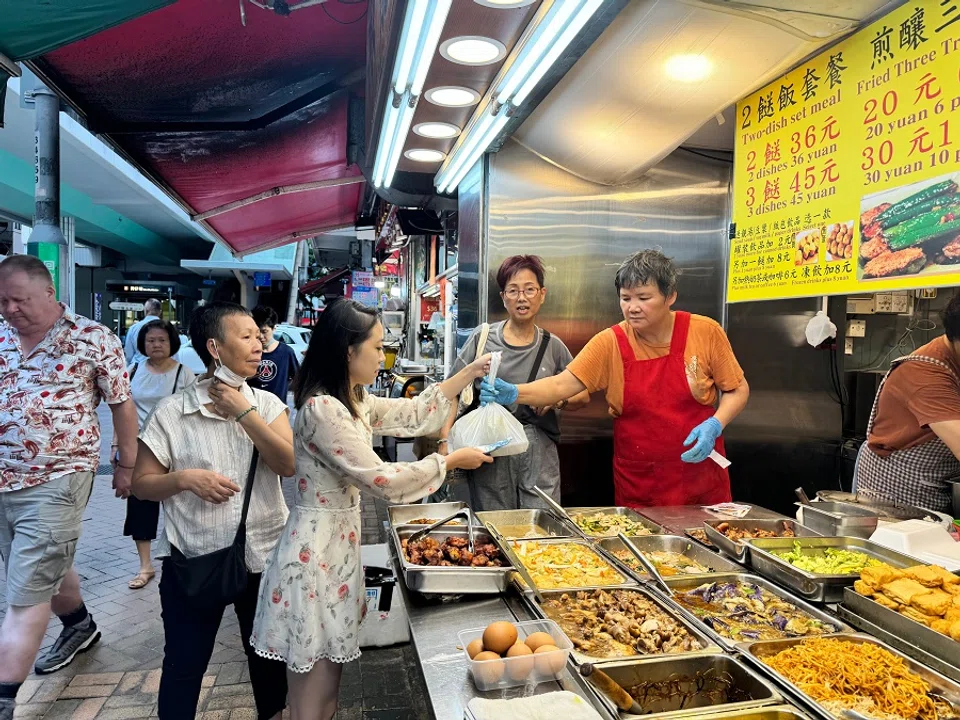 Feng Huaying (centre), who works in the media industry in Hong Kong, buys her lunch during the weekdays from a two-dish-rice eatery, July 2024. (SPH Media)