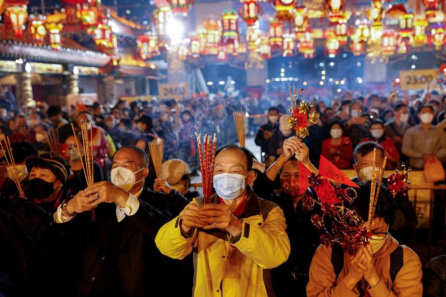 Worshippers wearing face masks make their first offerings inside the Wong Tai Sin Temple, in Hong Kong, China, 21 January 2023. (Tyrone Siu/Reuters)